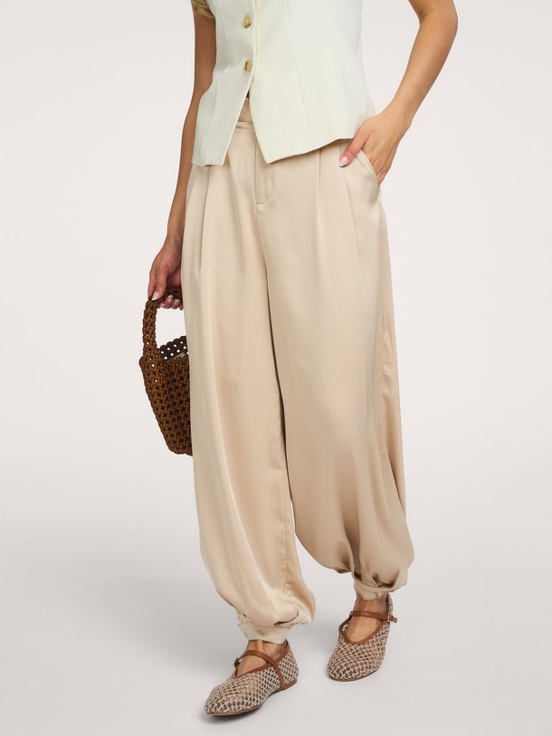 Ontdek de Fayla Drapy Satin Balloon Pants van Neo Noir bij Orangebag. Een elegante champagnekleurige broek met een luxe glans en een trendy balloon fit.