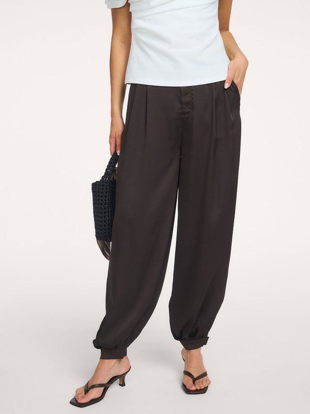 Ontdek de Fayla Drapy Satin Balloon Pants van Neo Noir bij Orangebag. Een stijlvolle donkerbruine broek met een luxe glans en trendy barrel fit.