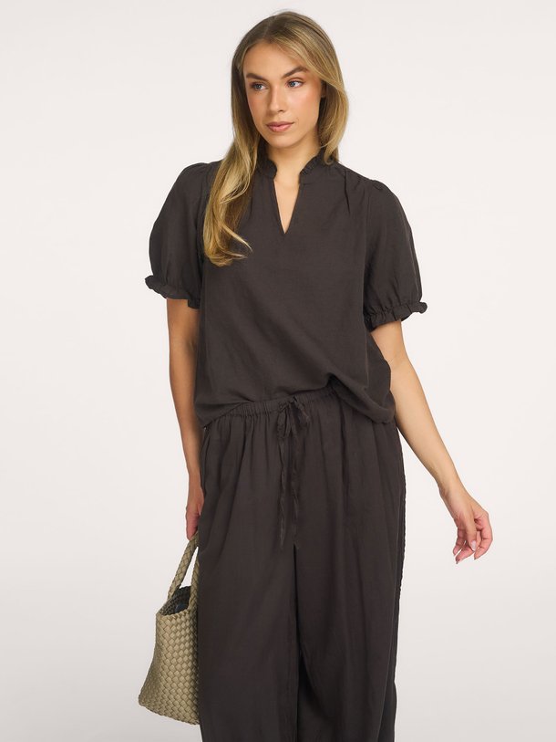 Shop de Neo Noir Odesa Linen Blouse bij Orangebag. Een tijdloze zwarte top met elegante pofmouwen en een flatterende V-hals. Perfect voor elke gelegenheid.