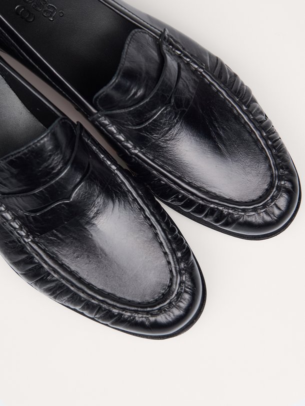Ontdek de Posa Penny Loafer Wrinkle in zwart leer bij Orangebag. Een tijdloze klassieker met een uniek rimpel-effect voor een moderne, stijlvolle twist.